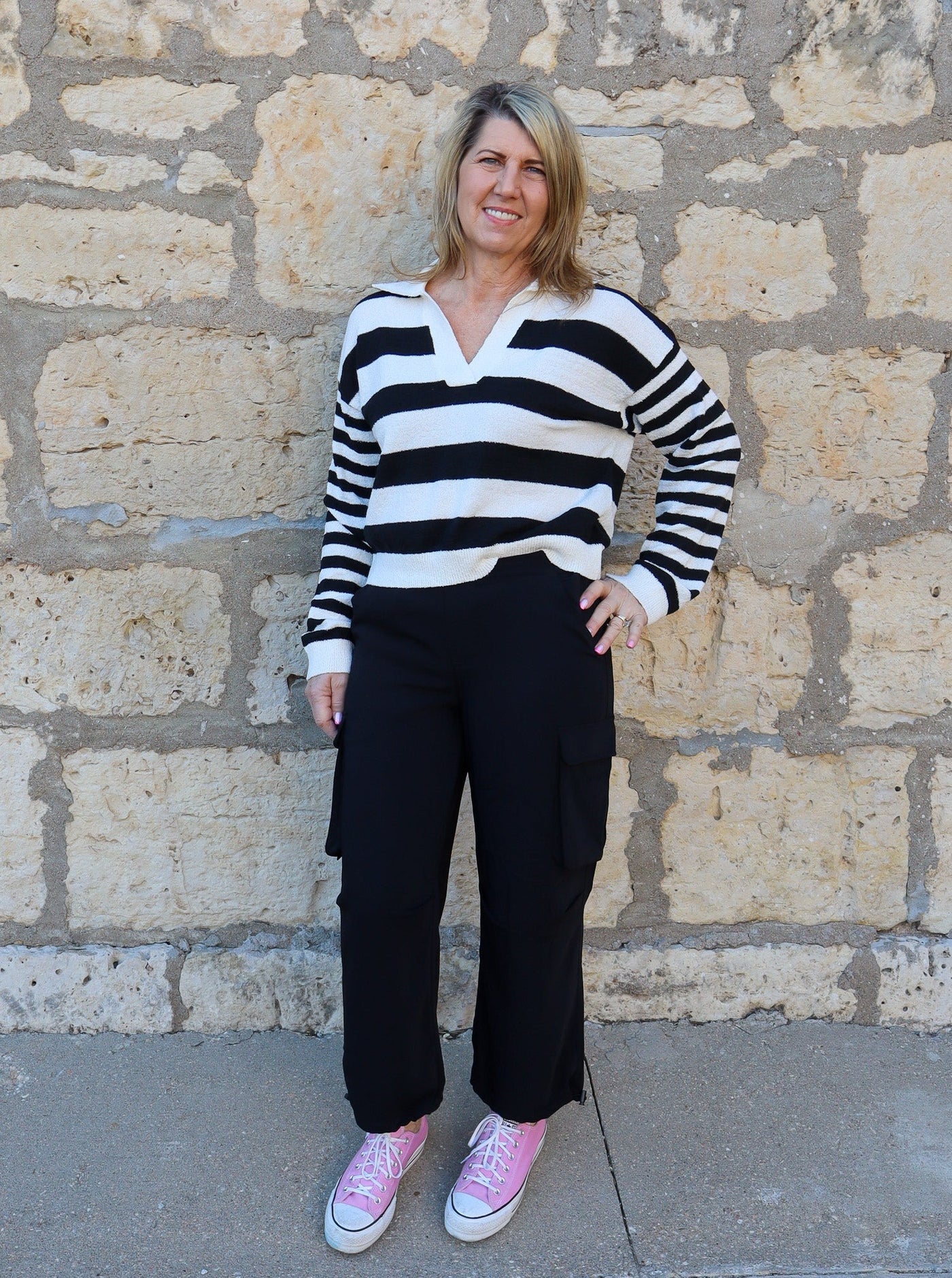 Model is wearing a cropped horizontal stripped black and white sweater. Worn with black cargo pants. 