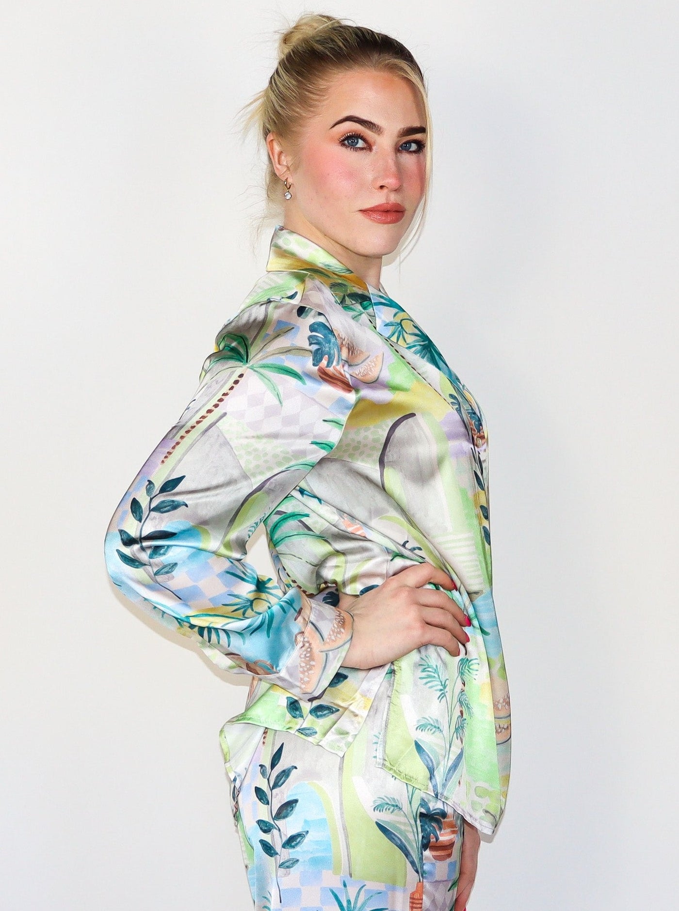 Model is wearing a silky button up collared blouse with a beachy/summery print. Top is paired with matching bottoms.