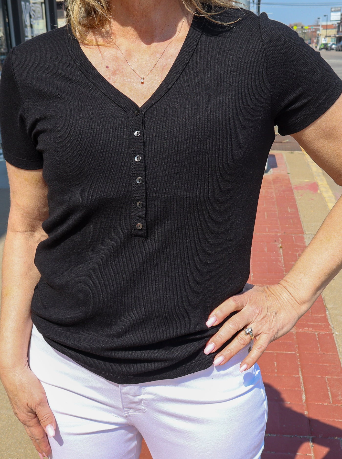 Model is wearing a ribbed fitted v-neck tee with button details on vneck.