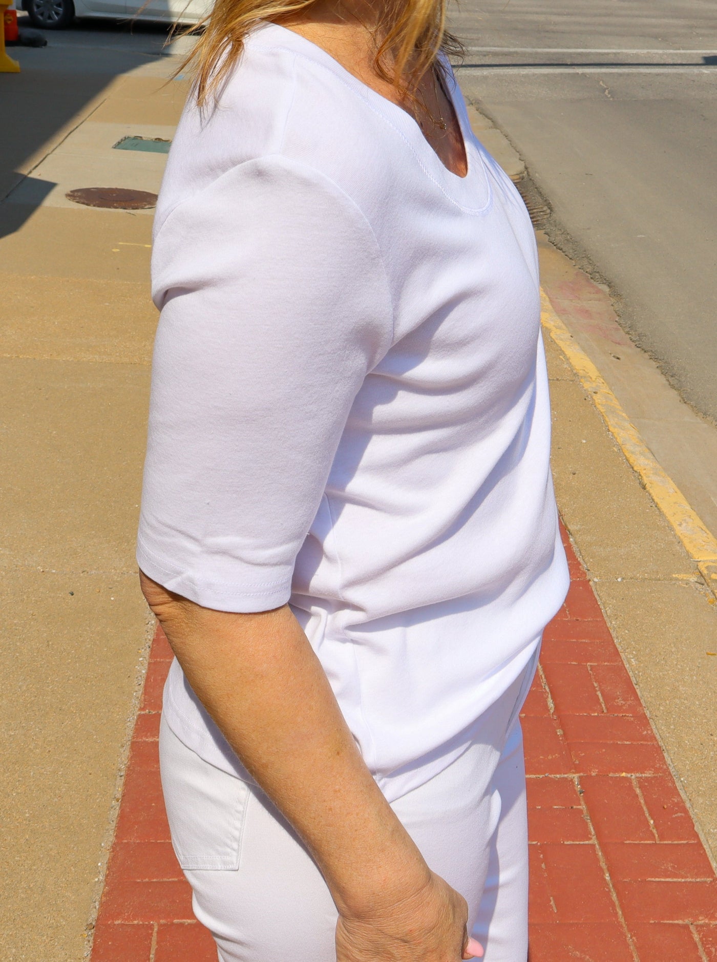 Model is wearing a fitted scoop neck white tee shirt.