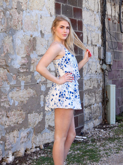 ZD241180Blue and white floral printed ruffled romper with cami straps and a v-neck line.