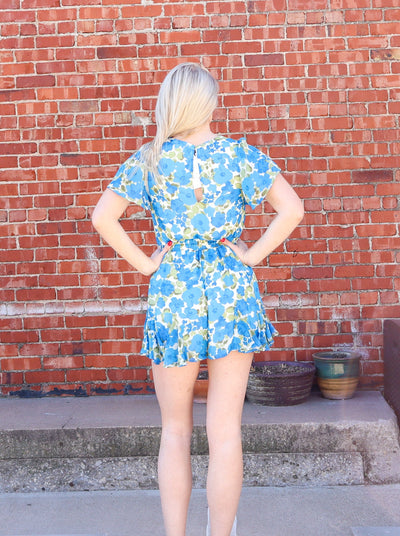 Blue white and green floral short sleeve mini romper with a deep neckline.