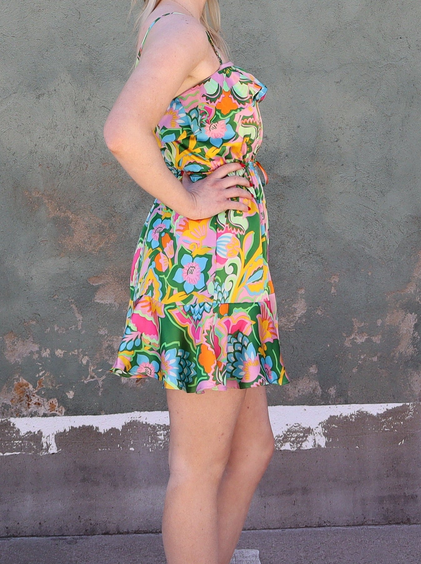 Model wearing a camisole strap tropical mini dress with ruffle detail. 