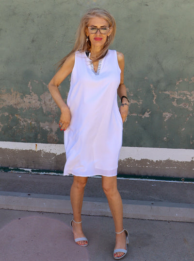 Model is wearing a white midi dress with a split neck and sparkle detail on it. Paired with heels.