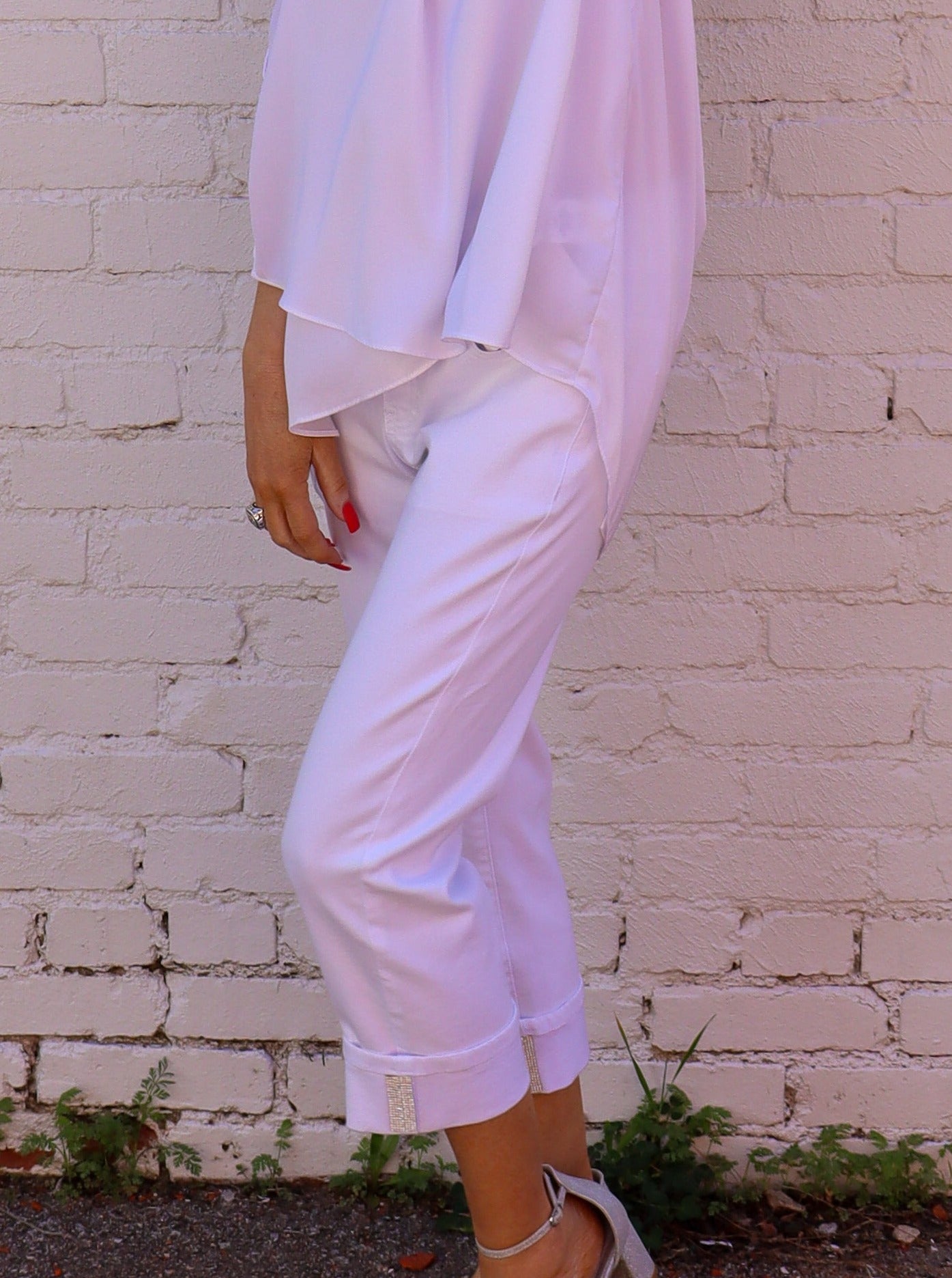 Model is wearing white pull. on jeans with sparkle details on the cuffs. Jeans are paired with a white blouse.