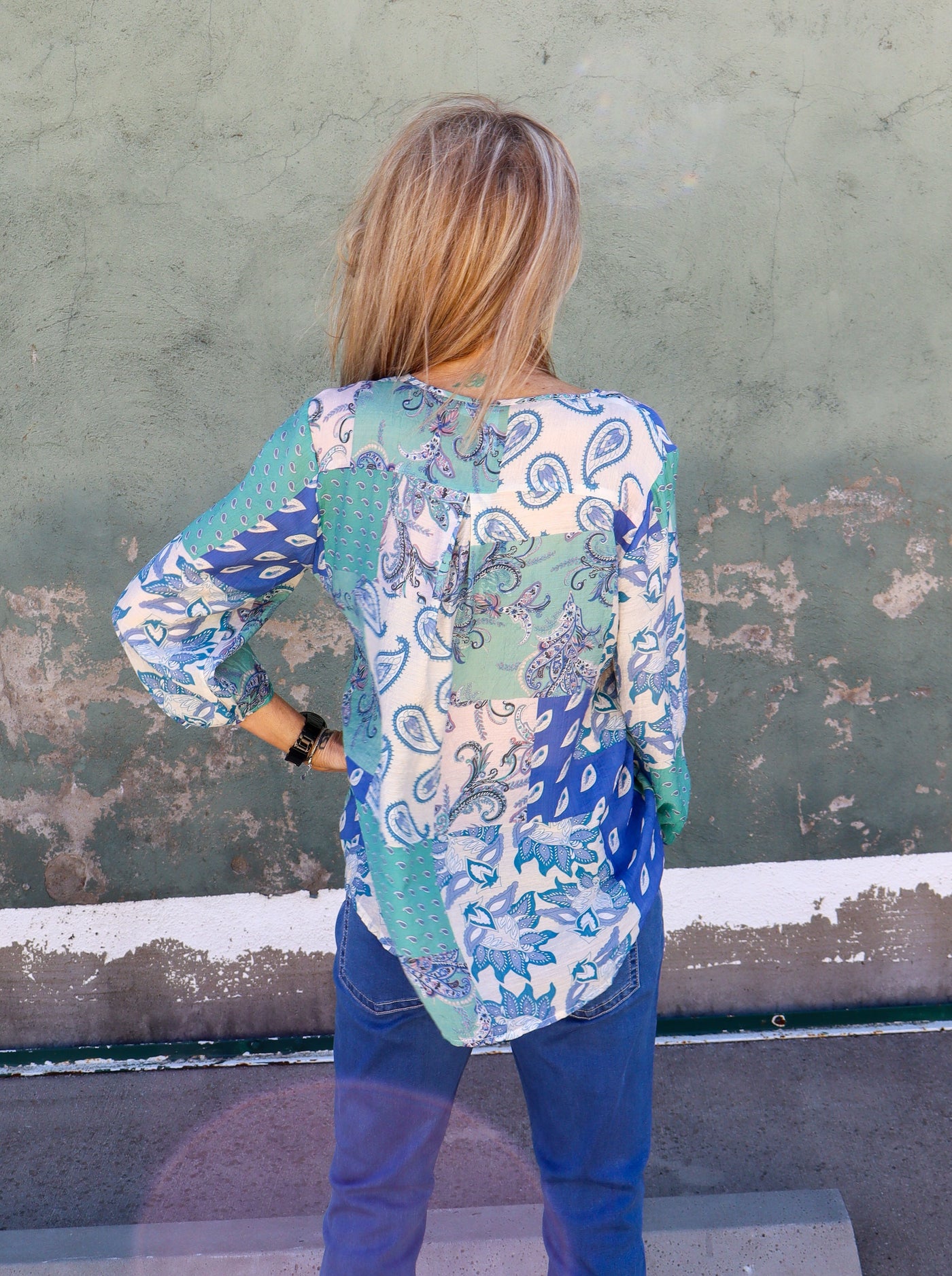 Model is wearing a blue and white paisley printed blouse, paired with blue jeans.