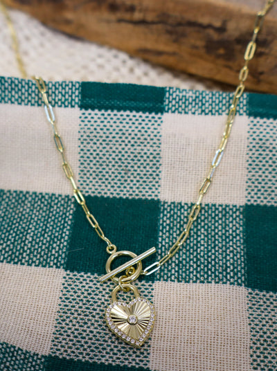 Gold chain necklace with a toggle clasp and heart pendant.