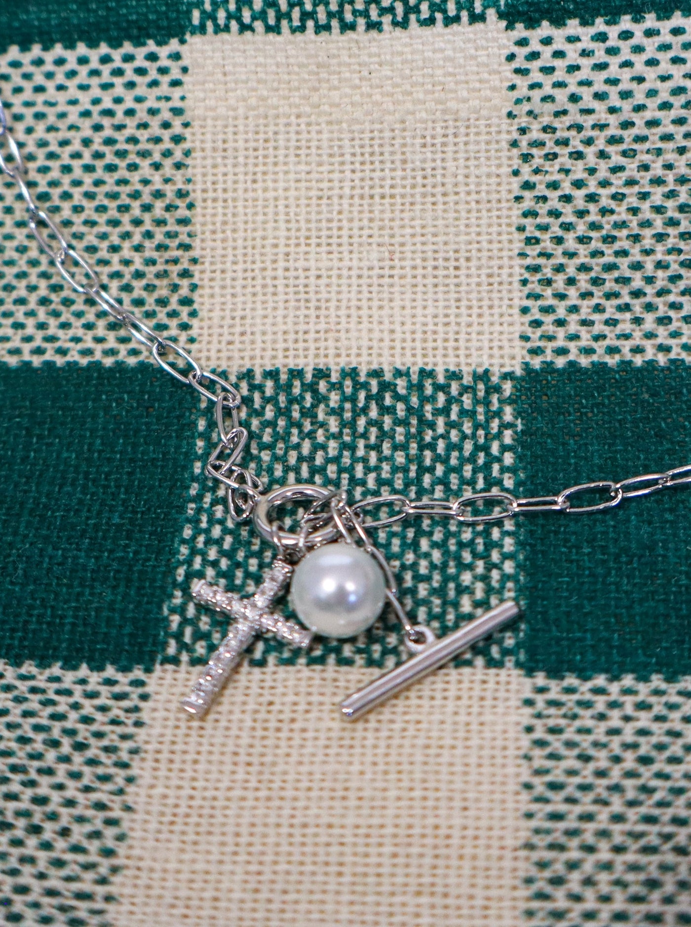 Silver chain necklace with a cross and pearl pendant.