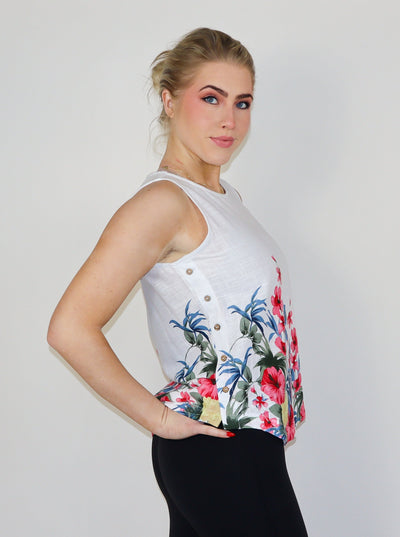 Model is wearing a white and floral printed linen tank, paired with black pants.