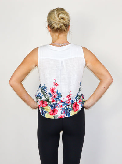 Model is wearing a white and floral printed linen tank, paired with black pants.