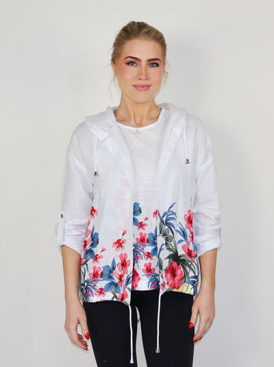 Model is wearing a white and floral printed hooded linen cardigan. Paired with a matching tank top and black pants.
