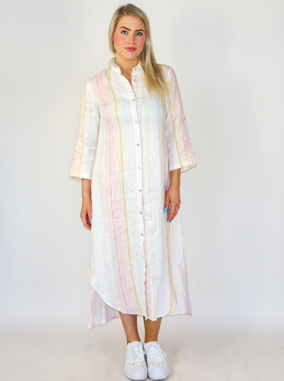 Model is wearing a pastel white, yellow, and cream striped long sleeve button up dress/duster. Worn with white sneakers,