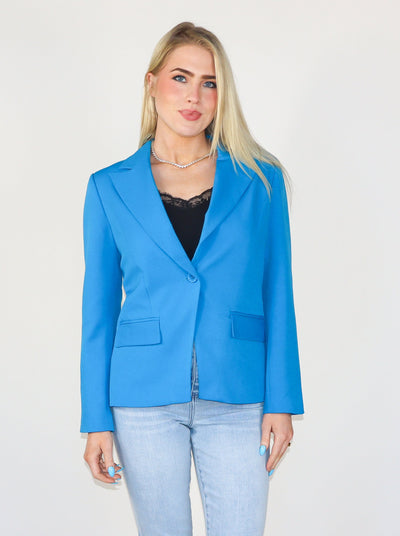 Model is wearing an electric blue fitted blazer: 27” HPS, Notched collar, Lined, Two front flap welt pockets, Single button closure, 3 button closure at cuffs, Subtle shoulder pads