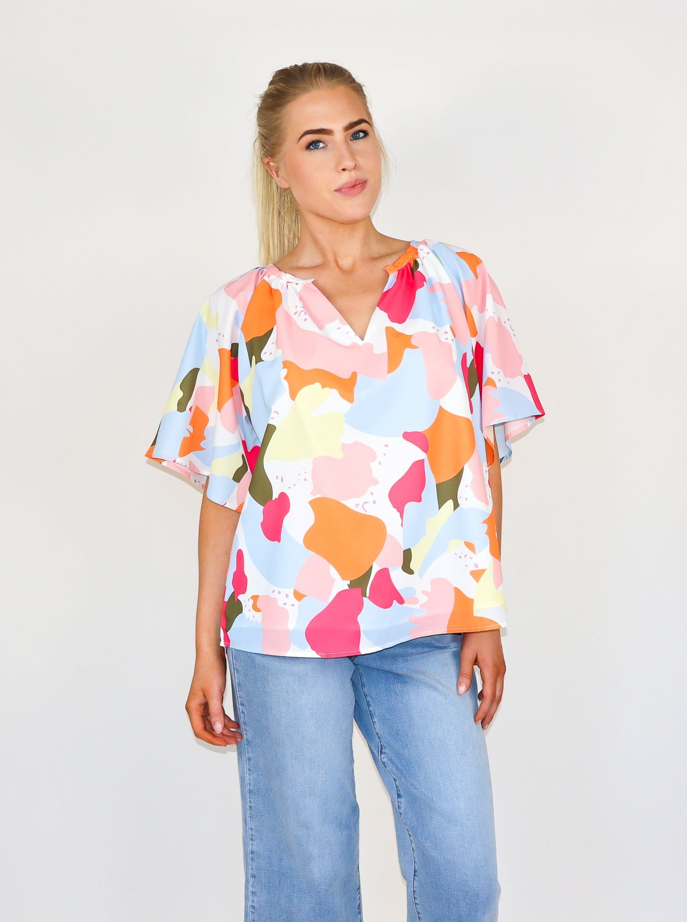 Model is wearing a multi color mosaic type printed v neck flowey blouse.