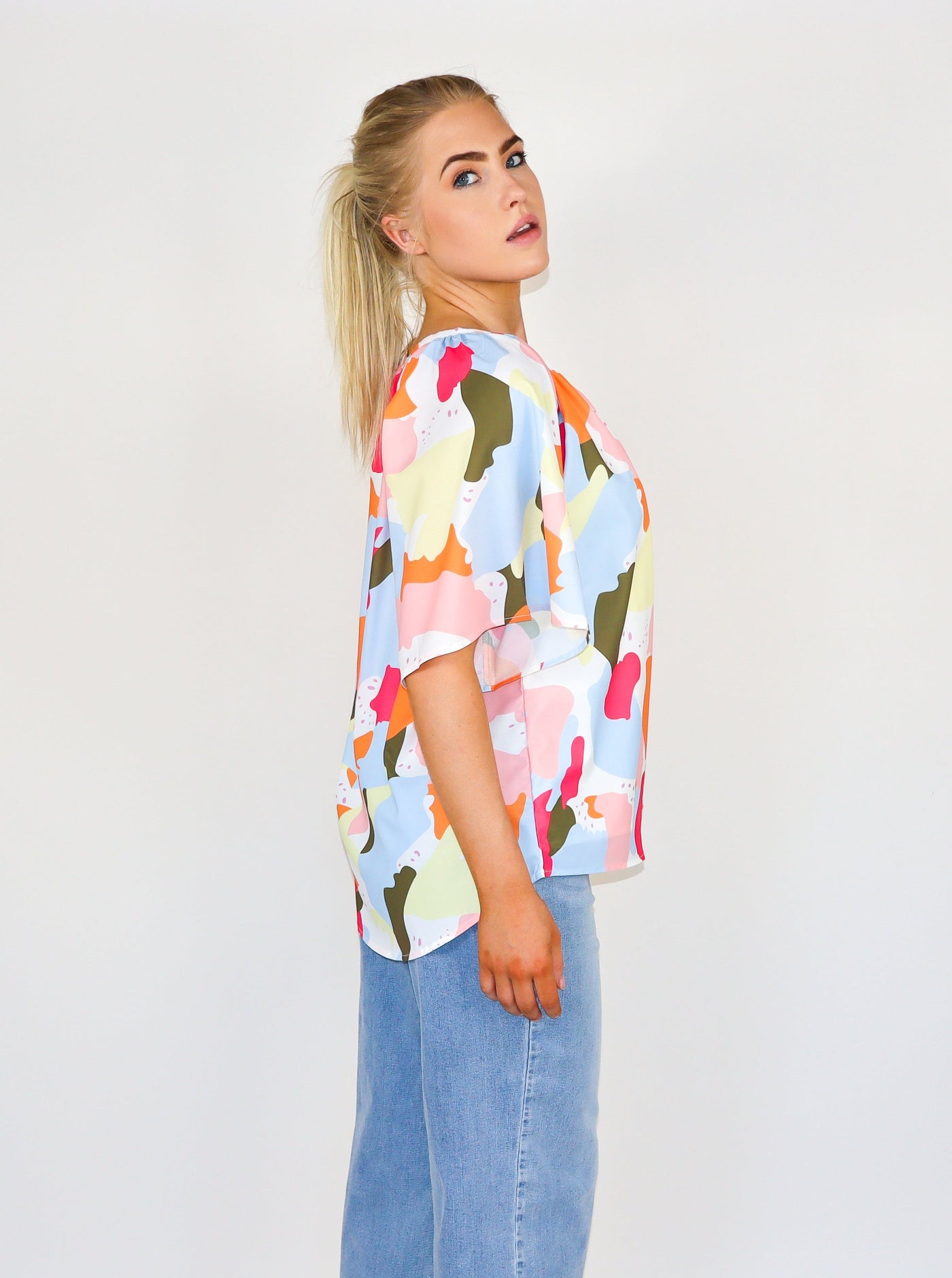 Model is wearing a multi color mosaic type printed v neck flowey blouse.