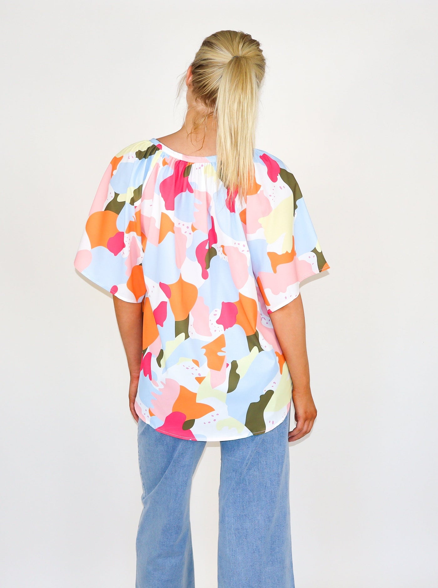 Model is wearing a multi color mosaic type printed v neck flowey blouse.