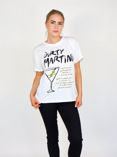 Model is wearing a white oversized Tee with the word "Dirty Martini" and a graphic of a dirty martini with additional text. Worn with black pants. 