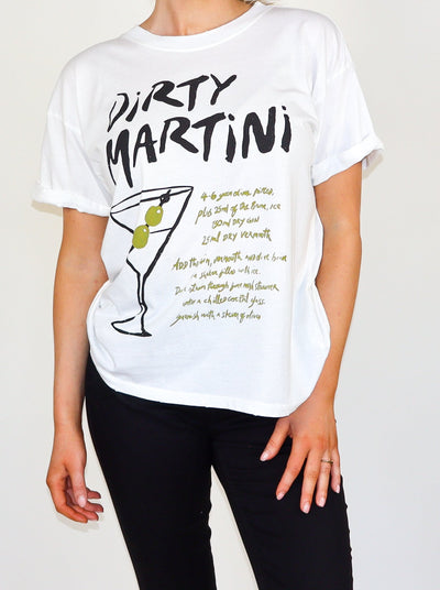 Model is wearing a white oversized Tee with the word "Dirty Martini" and a graphic of a dirty martini with additional text. Worn with black pants. 