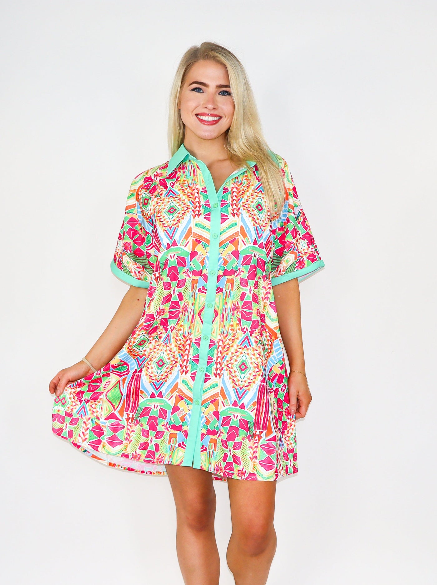 Model is wearing a button up geometric printed multi colored button up t-shirt dress.