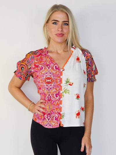 Model is wearing a multi pattern button up v-neck blouse with puff sleeves. 