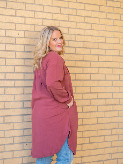 A model wearing a rose colored long shacket with a button closure. The model has it paired with a graphic tee and light wash jeans.