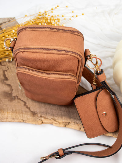 A light brown vegan leather crossbody bag with a detachable snap pouch.