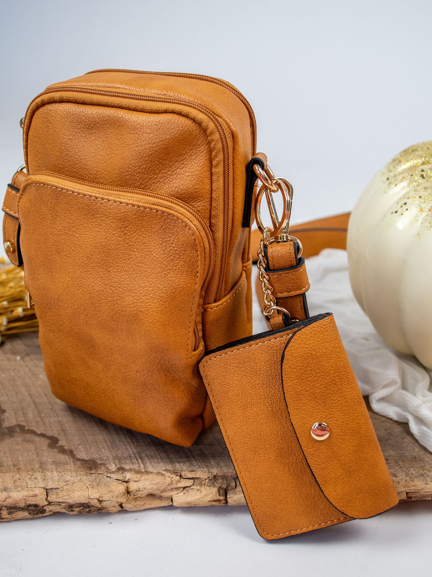 A pumpkin brown vegan leather crossbody bag with a detachable snap pouch.