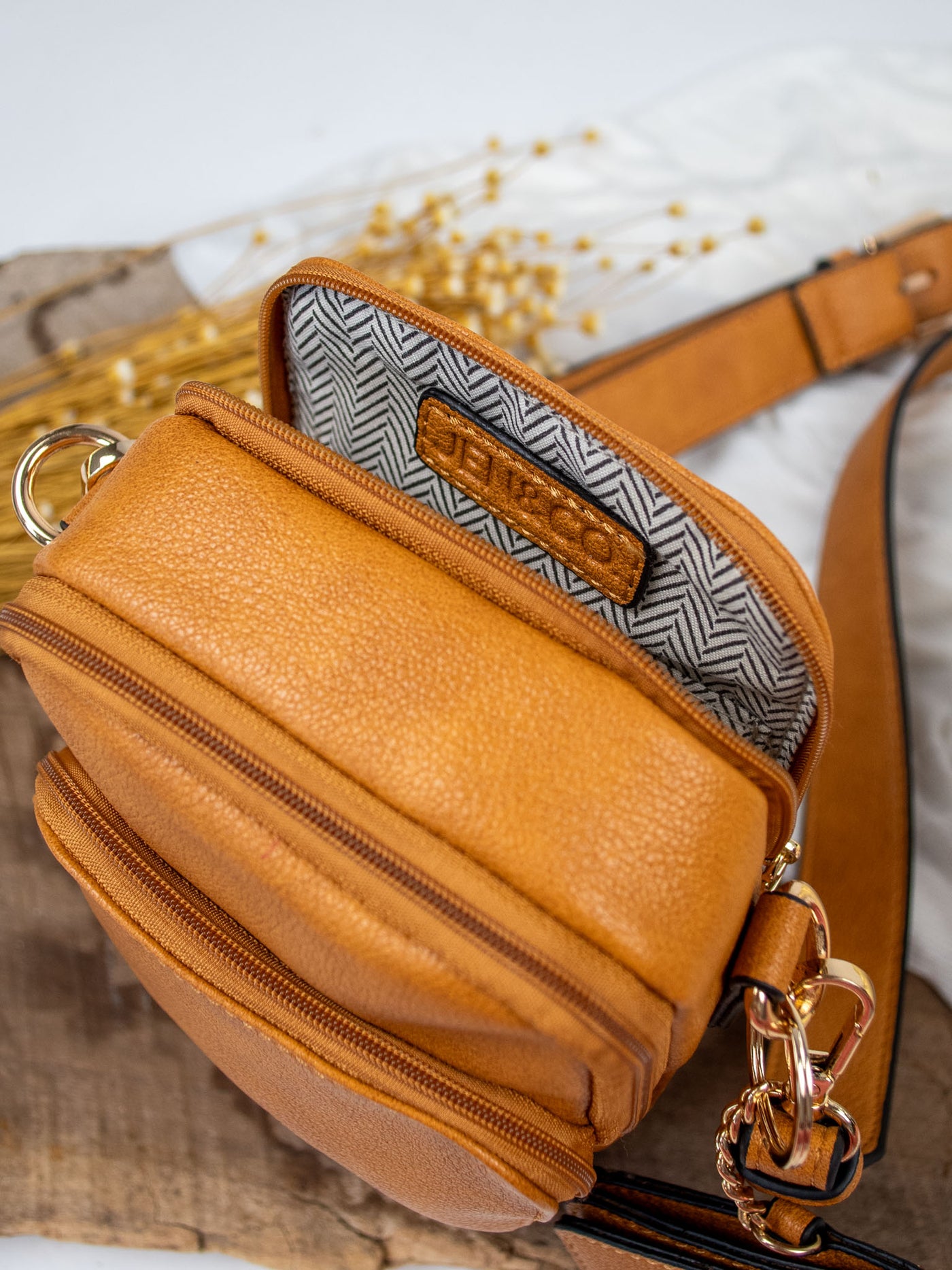 A pumpkin brown vegan leather crossbody bag with a detachable snap pouch.