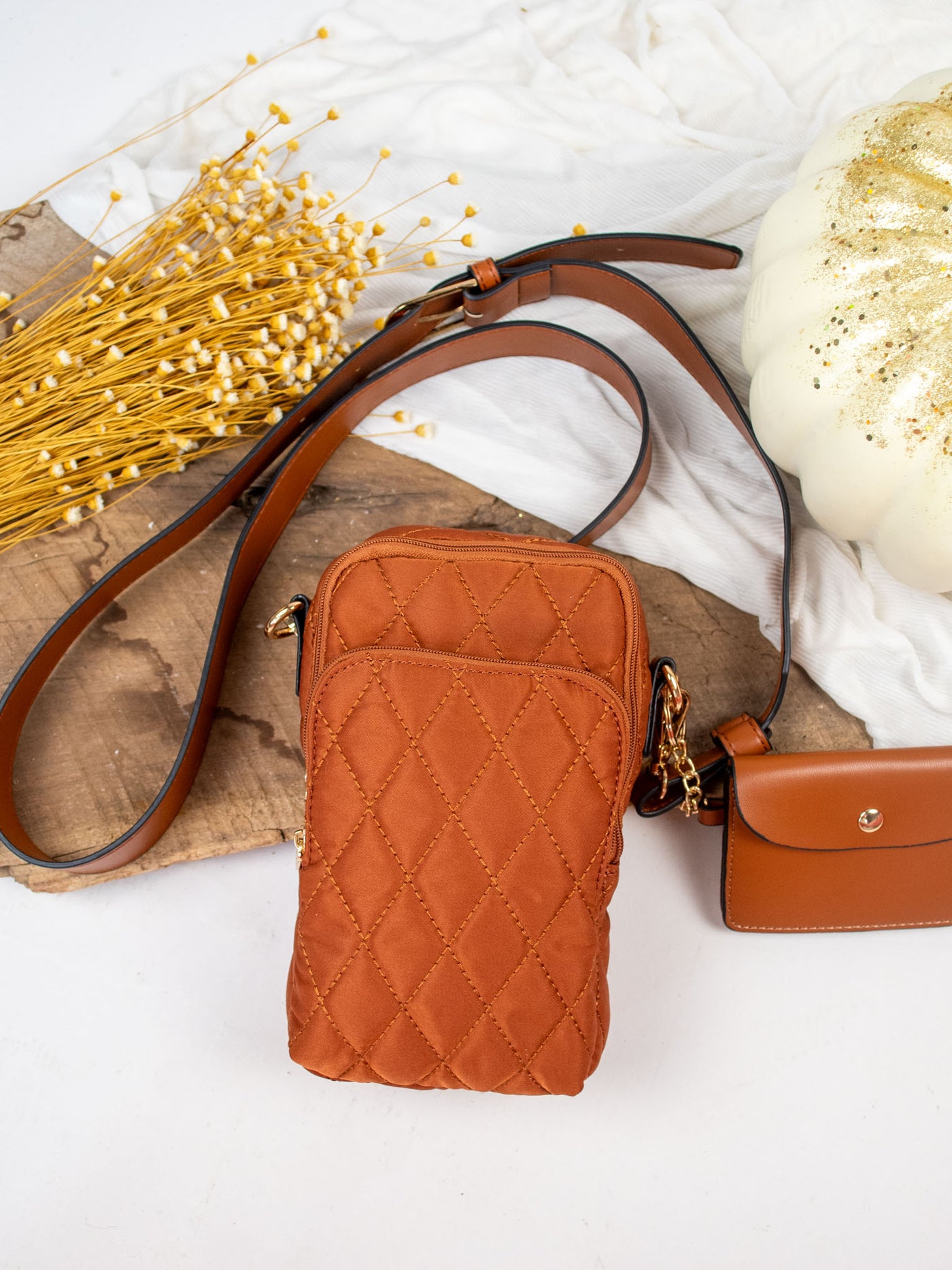 A medium brown quilted crossbody bag with a detachable snap pouch.