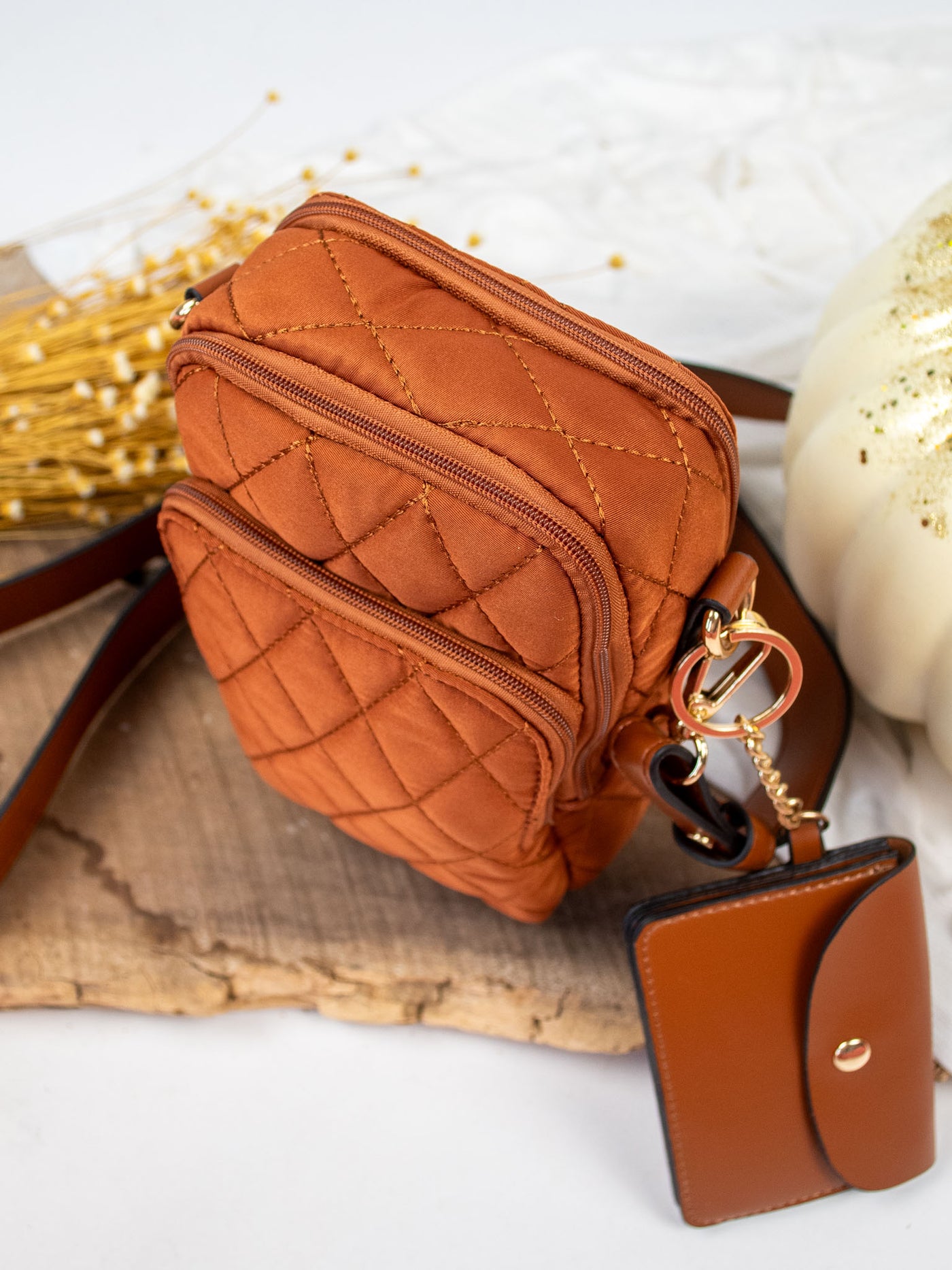 A medium brown quilted crossbody bag with a detachable snap pouch.
