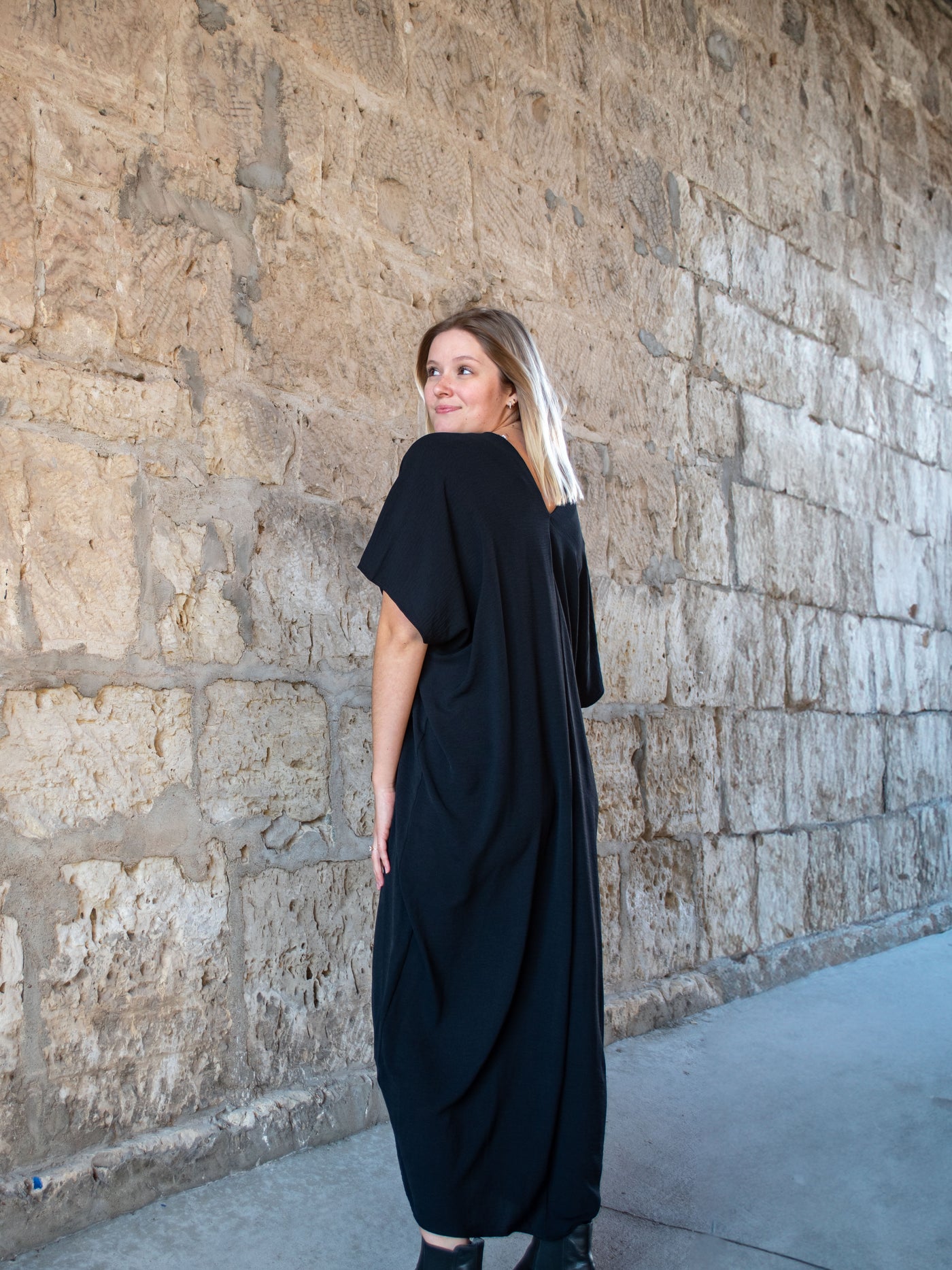 A model wearing a black silk midi kaftan. The model has it paired with black booties.