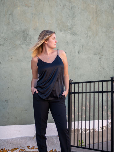 A model wearing a black silk tank with adjustable spaghetti straps. The model is wearing it with black trousers.