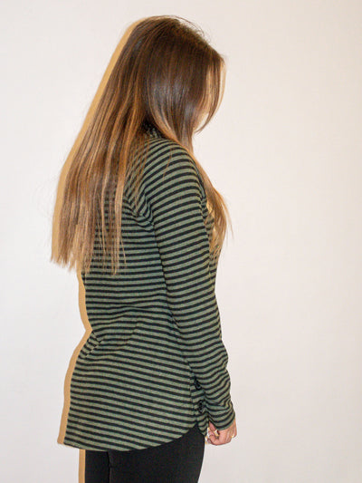 A model wearing an olive and black striped top with button details on the side. The model has it paired with black leggings.