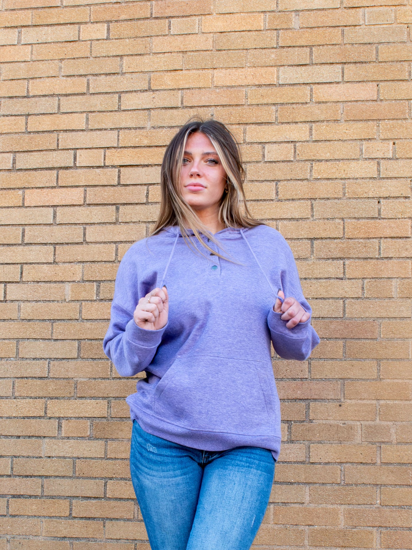 A model wearing a light purple fleece hoodie. The model has it paired with a pair of medium wash jeans.