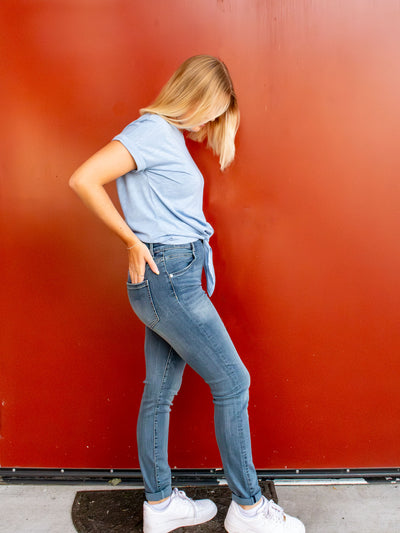 A model wearing a pair of light wash skinny jeans. She has it paired with a light blue t-shirt and white sneakers. 