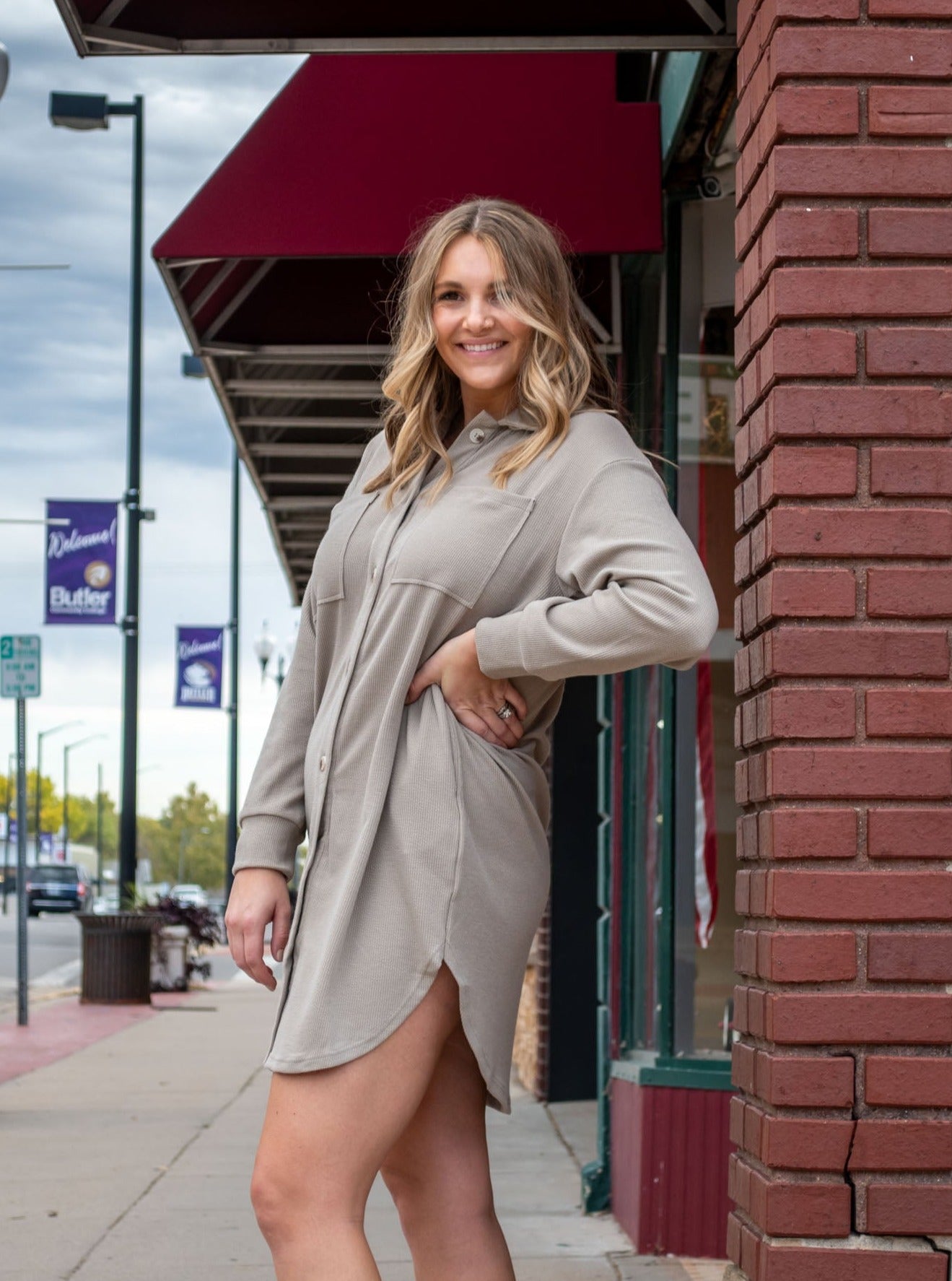 A model wearing an oatmilk colored button down dress. The model has it paired with black booties.