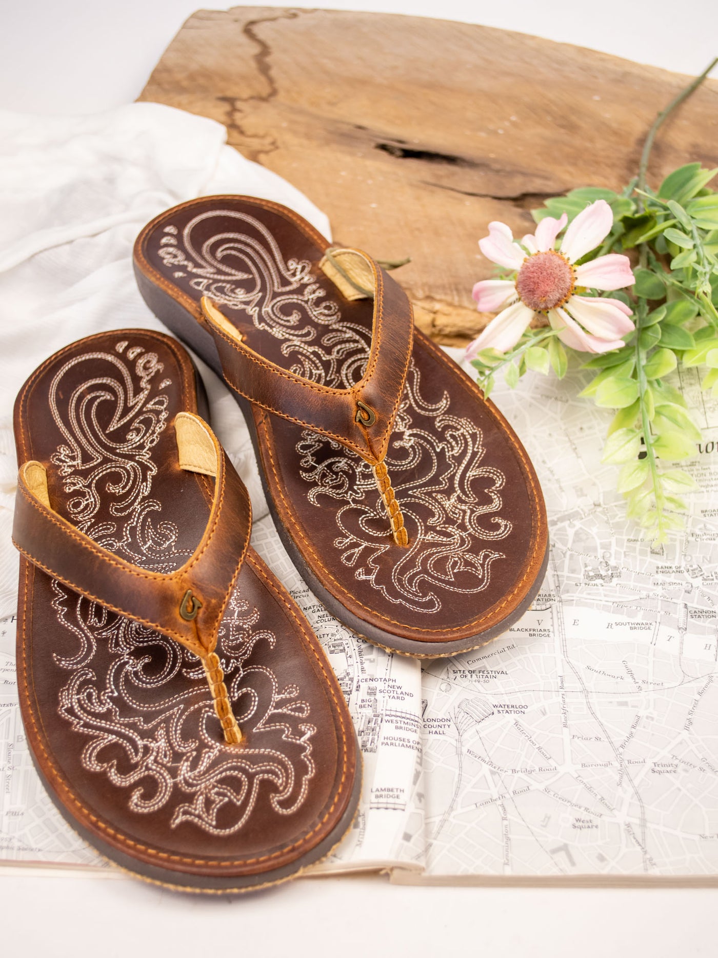 A brown leather sandal with stitching details and between the toe strap.