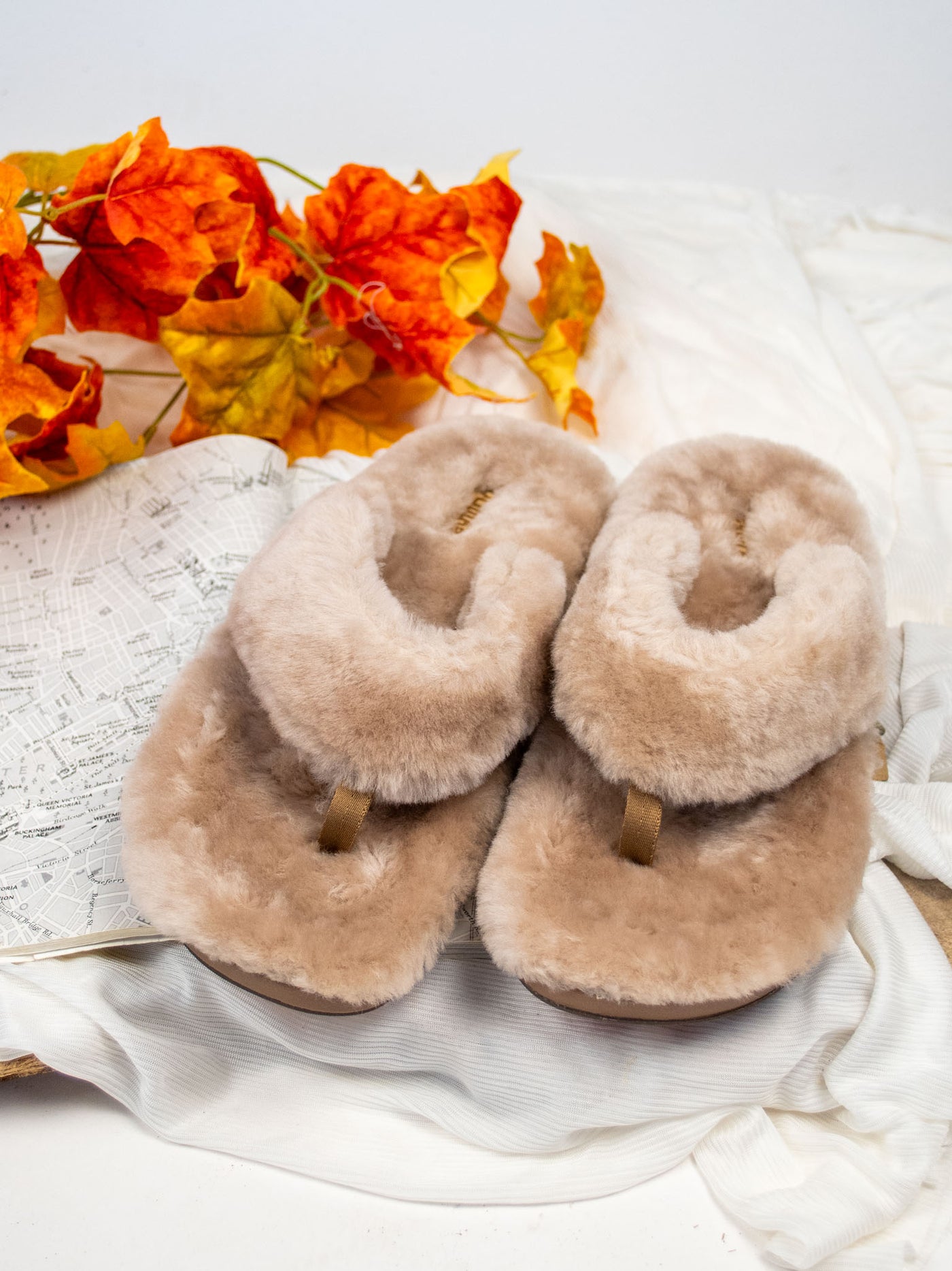 A pair of tan slipper sandals with all over fur and a rubber sole.