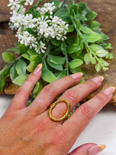 A gold ring featuring a statement oval piece in the center.