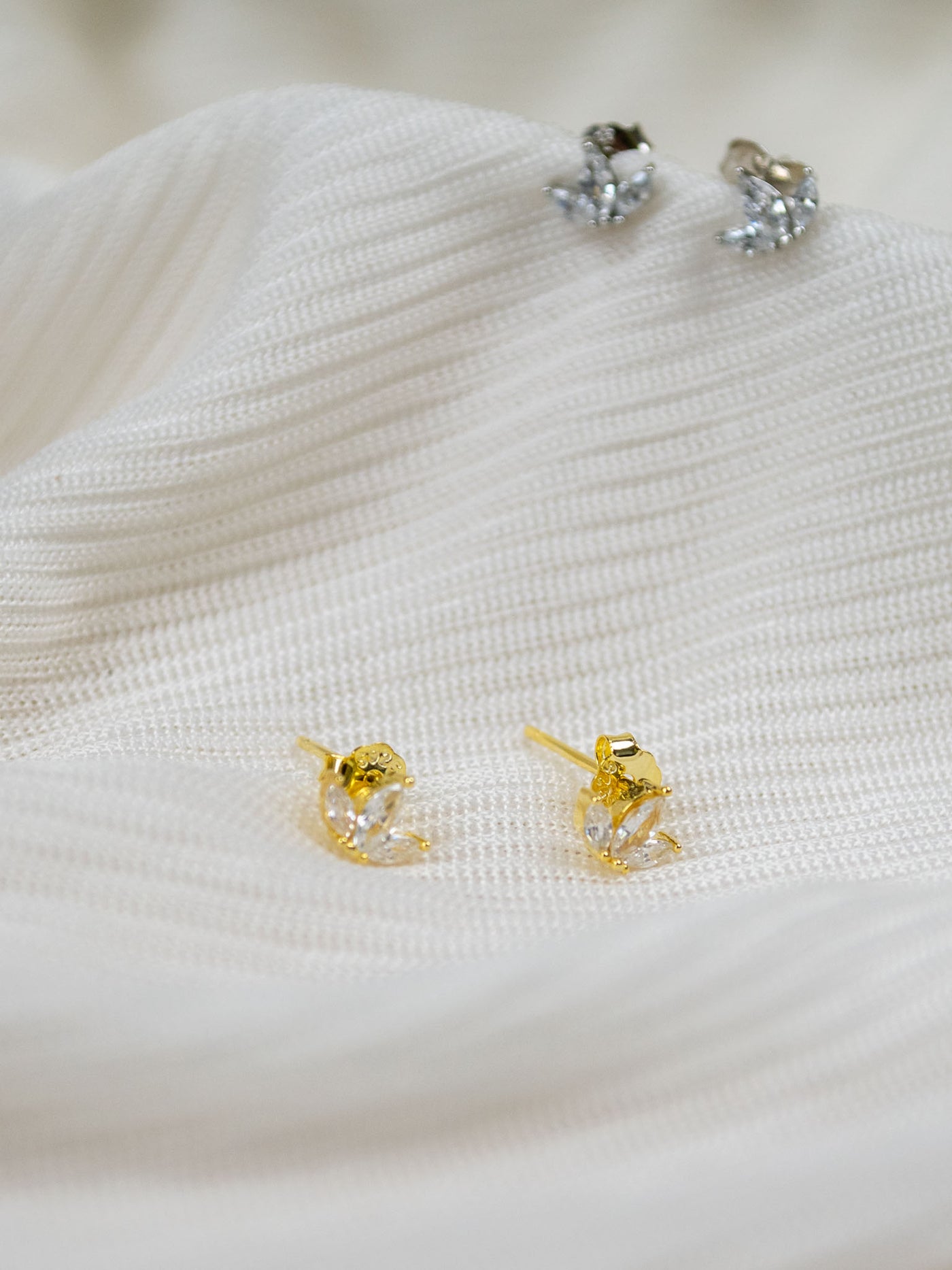 Two pairs of silver and gold CZ stone stud earrings in a lotus shape.