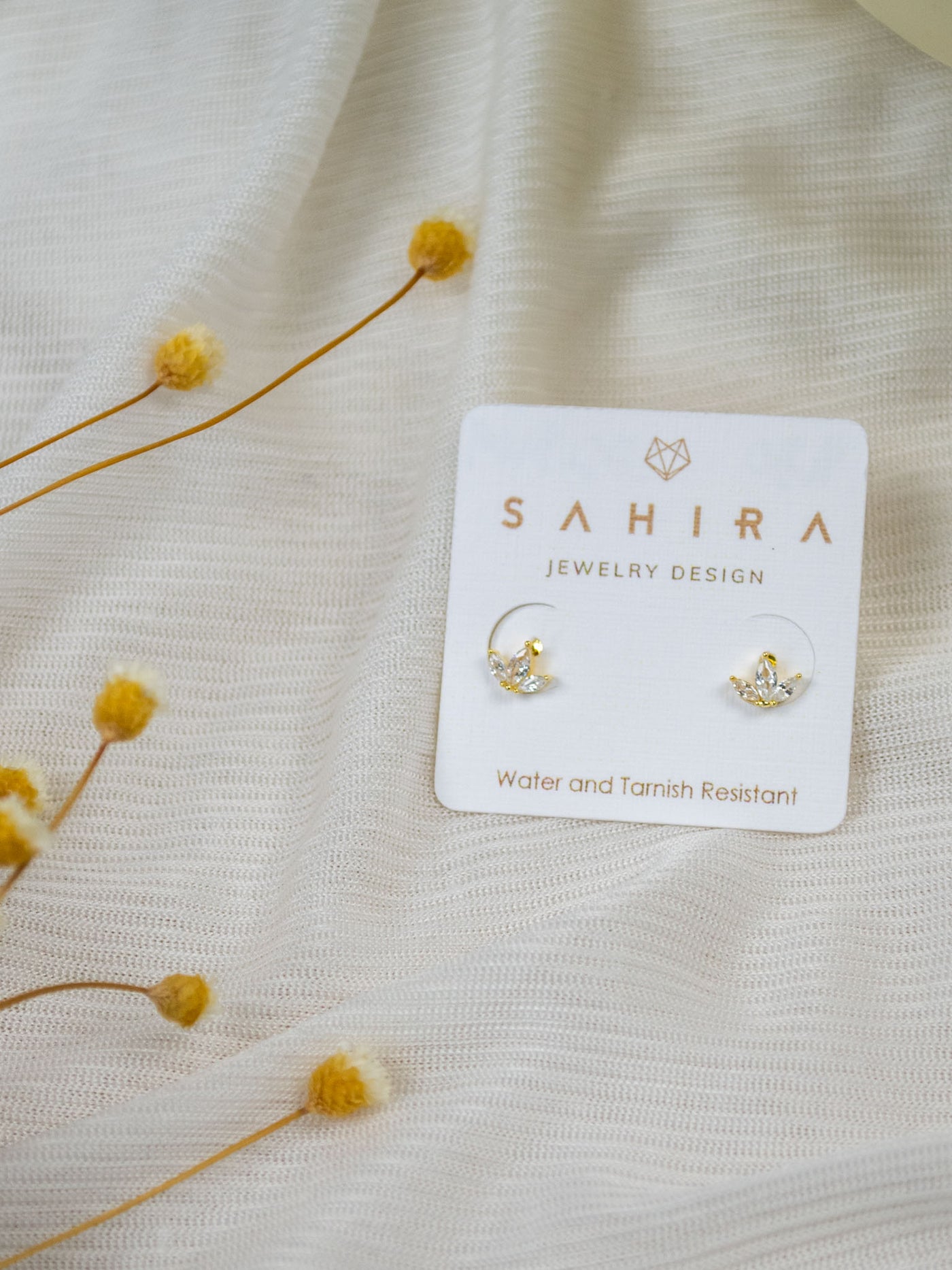 A pair of gold CZ stone stud earrings in a lotus shape.