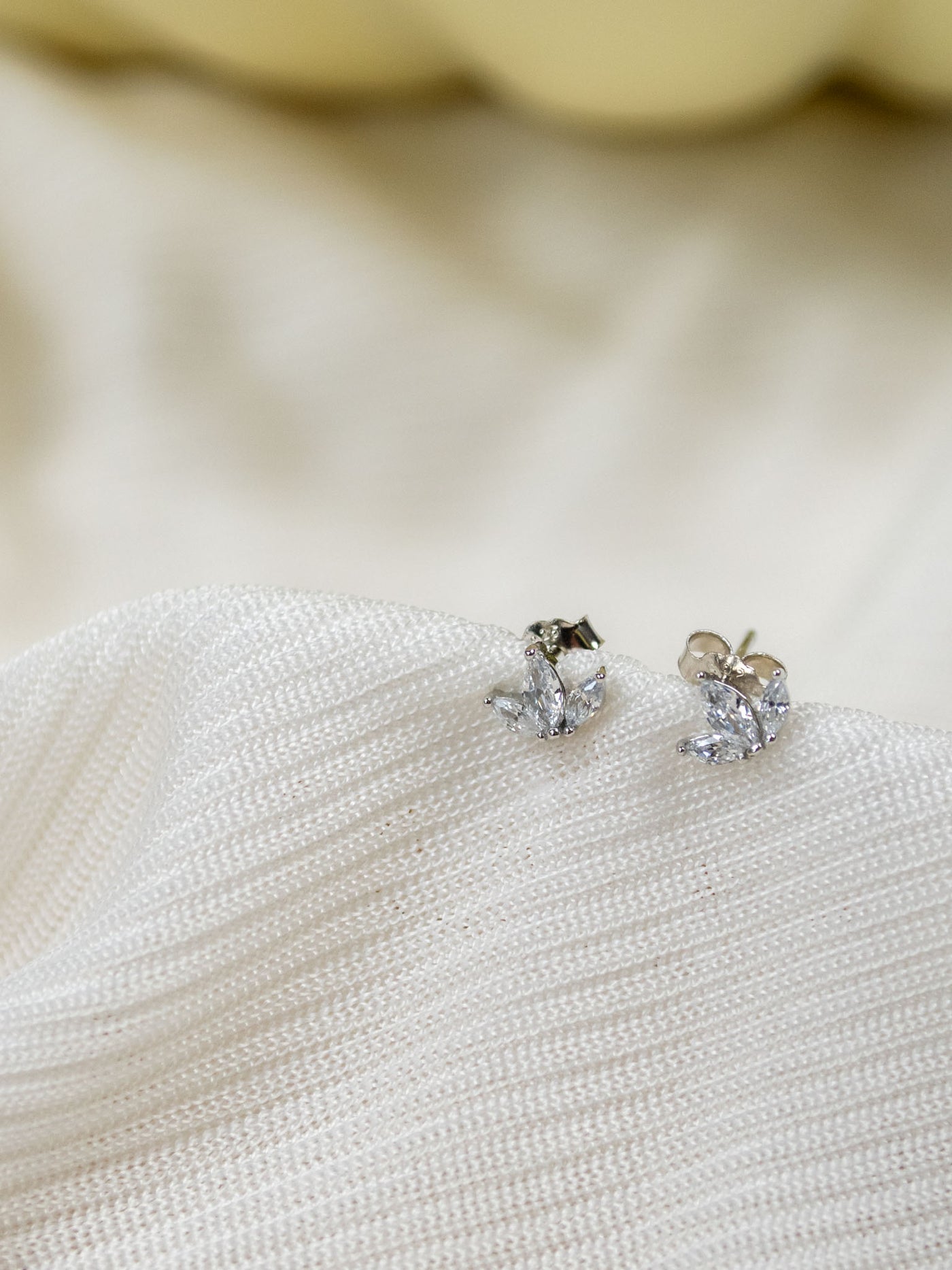 A pair of silver CZ stone stud earrings in a lotus shape.