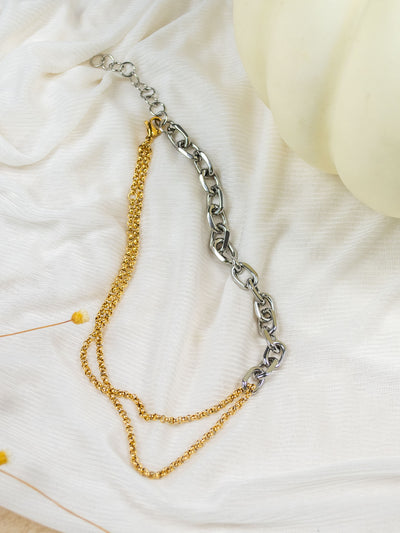 A two tone chain necklace with two small gold chains on one side and a thick silver link on the other side. 