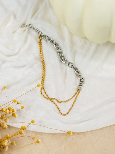 A two tone chain necklace with two small gold chains on one side and a thick silver link on the other side. 
