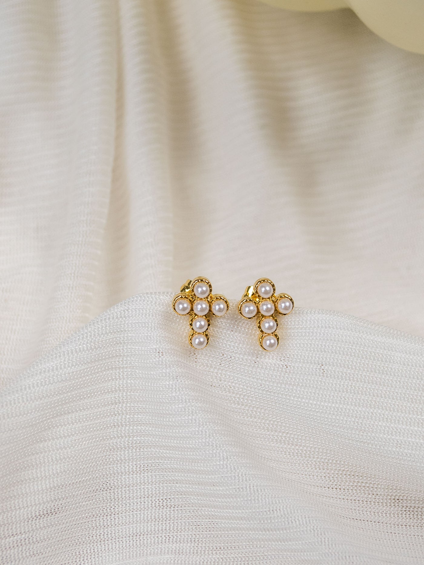 A pair of gold mini pearl cross studs.