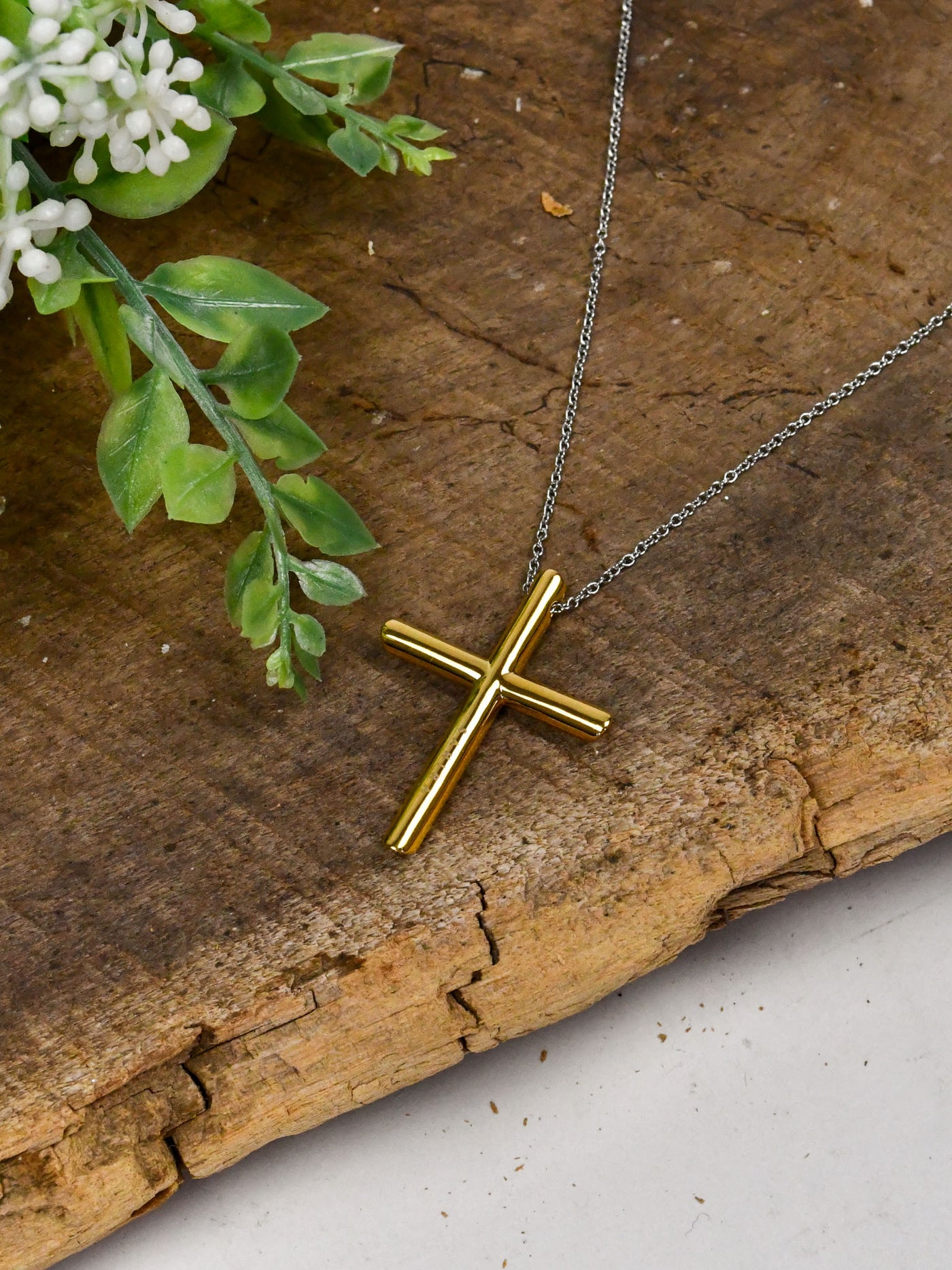 A necklace featuring a gold cross and silver chain.