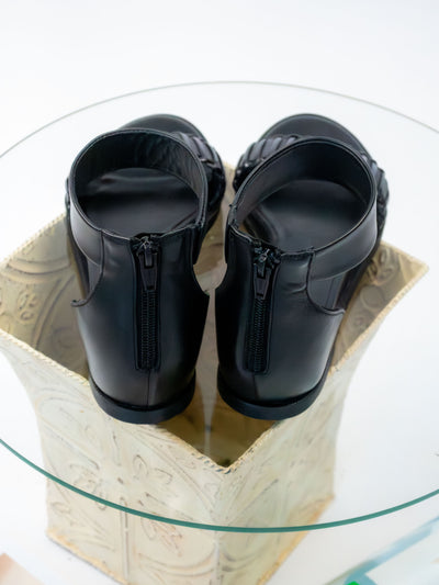 A pair of black leather wedge sandals.