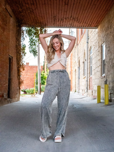 A model wearing a high waisted, drawstring gray sweatpants. She has them paired with a crop top and platform sandasl.