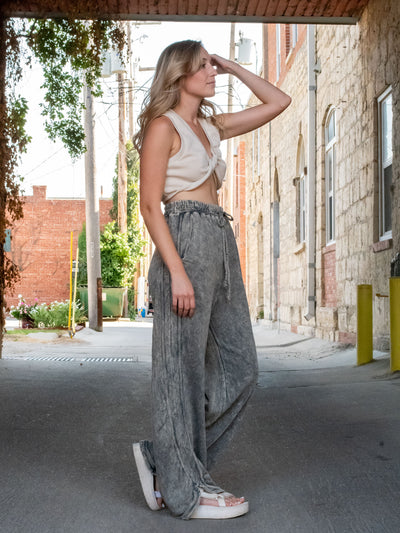 A model wearing a high waisted, drawstring gray sweatpants. She has them paired with a crop top and platform sandasl.