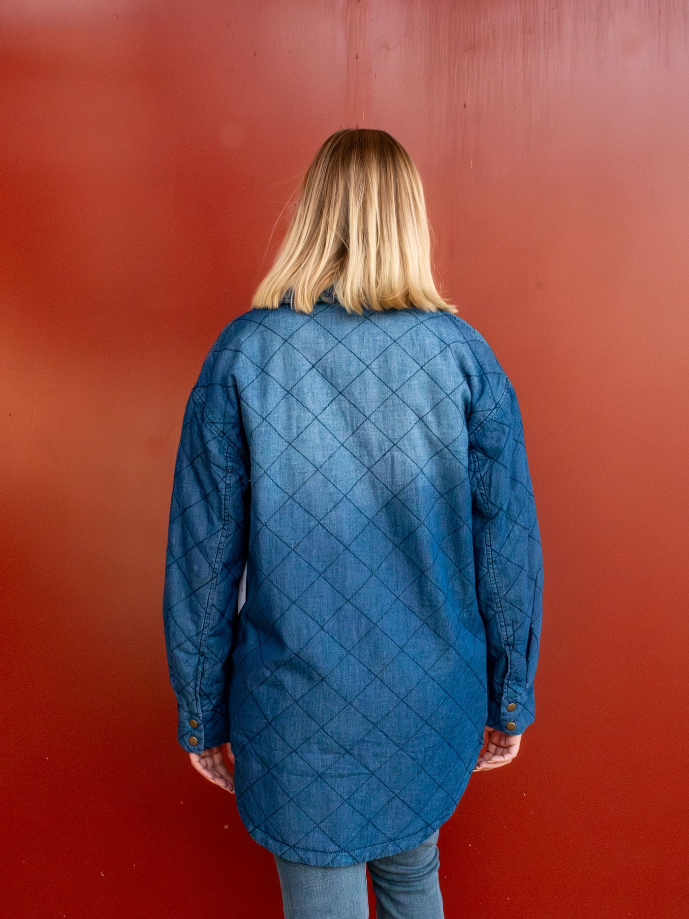 A model wearing a blue quilted shacket that buttons down the front. The model paired it with light wash jeans.